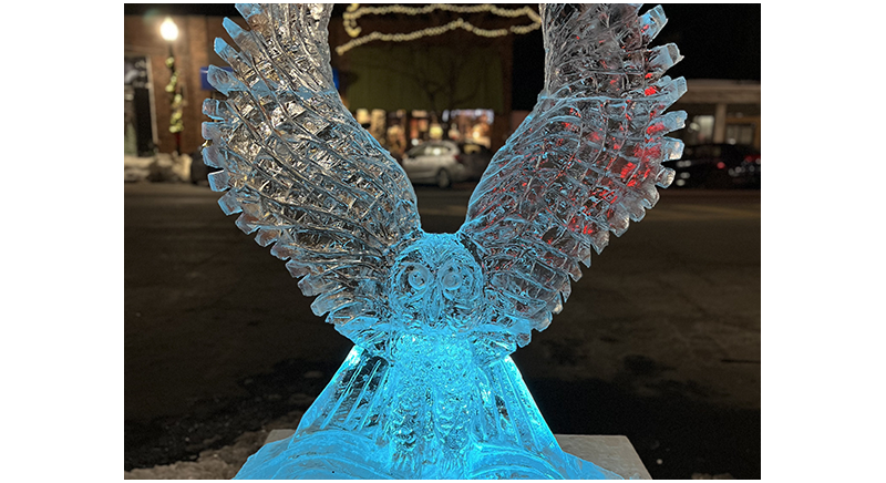 an owl ice sculpture carved by Billy Poe illuminated on Main Street for Winter Carnival